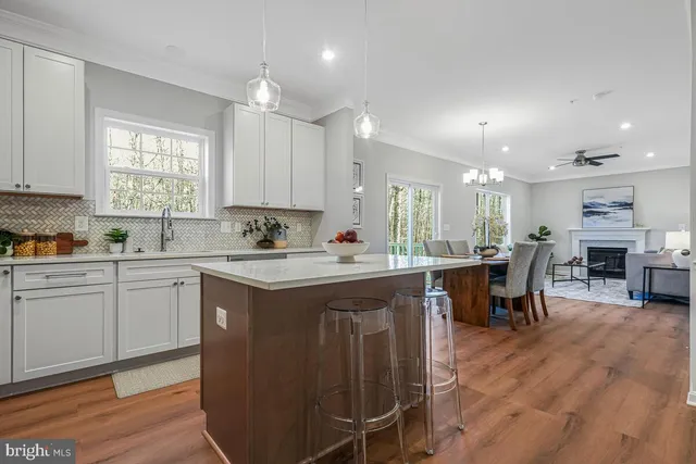 a kitchen with stainless steel appliances granite countertop a stove top oven a sink dishwasher a dining table and chairs with wooden floor