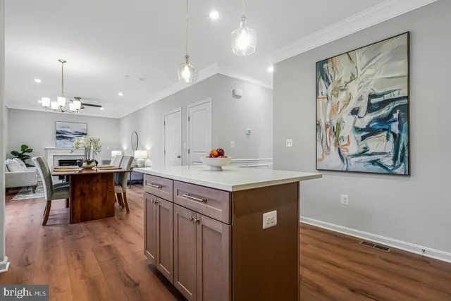 a kitchen with granite countertop a stove a sink a dining table and chairs with wooden floor