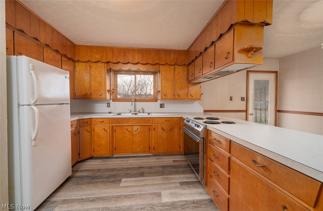 3336 Broad Run Dairy Road Northwest Dover, OH 44622 - Photo 14 of 26 Kitchen with freestanding refrigerator, light countertops, electric stove, wood finish cabinetry, and a textured ceiling