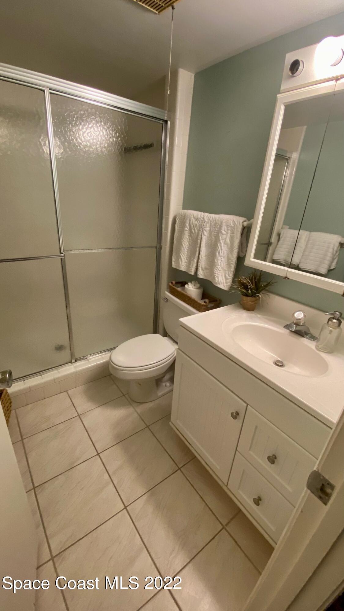 5050 Ocean Beach Boulevard, Unit 104 Cocoa Beach, FL 32931 - Photo 11 of 15 a bathroom with a granite countertop sink toilet and shower