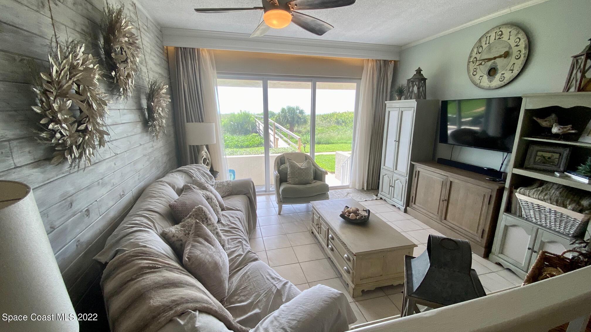 5050 Ocean Beach Boulevard, Unit 104 Cocoa Beach, FL 32931 - Photo 2 of 15 a living room with furniture and a large window