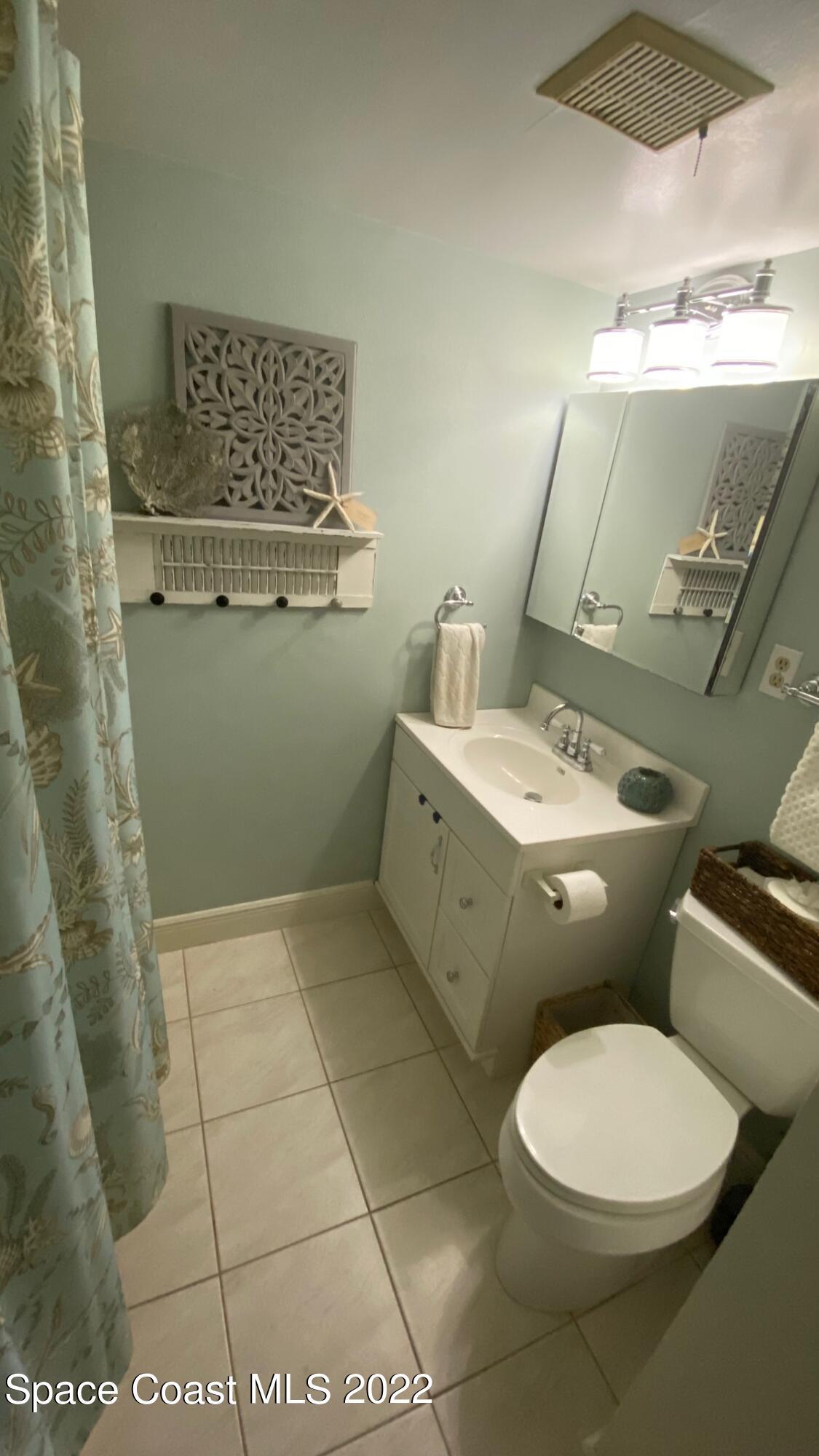 5050 Ocean Beach Boulevard, Unit 104 Cocoa Beach, FL 32931 - Photo 9 of 15 a bathroom with a toilet sink and mirror