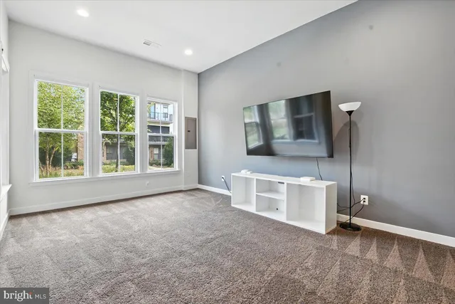 a view of an empty room with a window and a kitchen