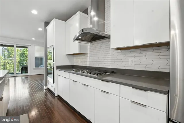 a kitchen with granite countertop a stove a sink dishwasher and white cabinets with wooden floor