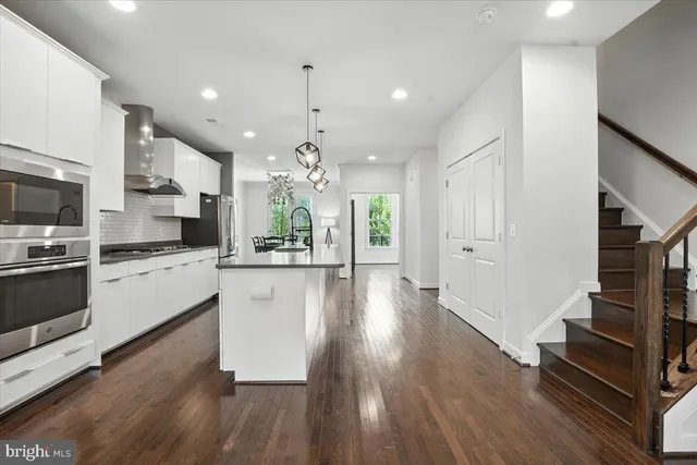 a kitchen with white cabinets stainless steel appliances and wooden floor