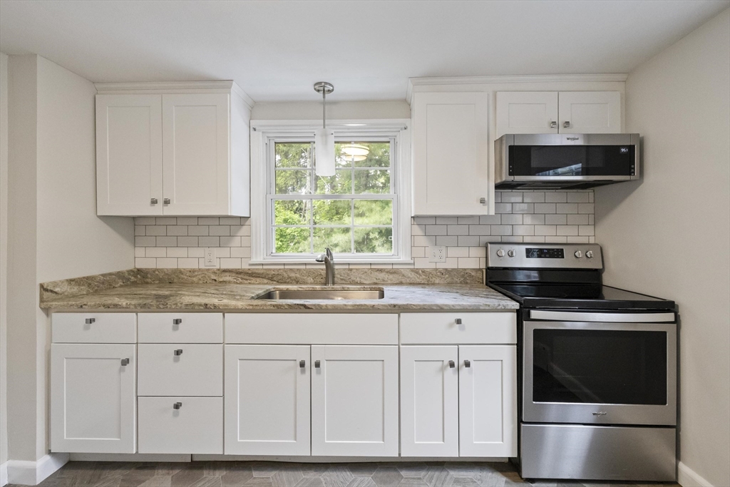 1652 Parker Street Springfield, MA 01128 - Photo 6 of 22 a kitchen with granite countertop a sink stainless steel appliances and white cabinets