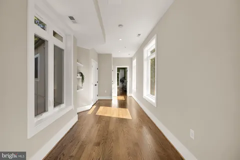 a view of a hallway with wooden floor and windows