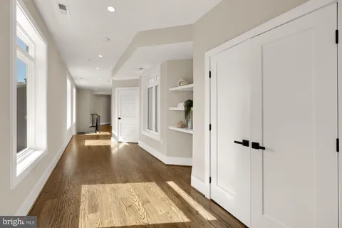 a view of a hallway with wooden floor and a bathroom