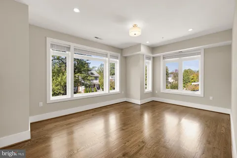 a view of an empty room with wooden floor and windows