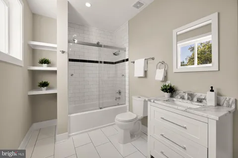 a bathroom with a granite countertop sink a toilet a mirror a vanity and shower
