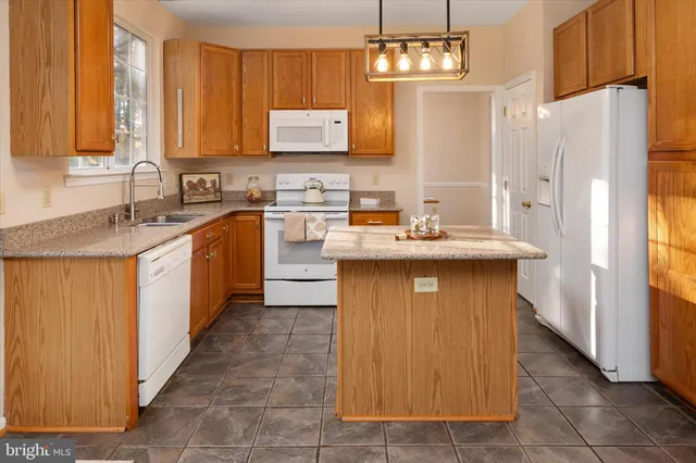 a open kitchen with granite countertop a stove a sink a refrigerator dining table and chairs