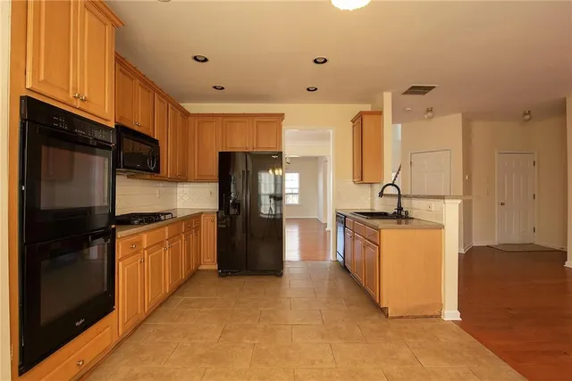 a kitchen with stainless steel appliances granite countertop a refrigerator a stove and a sink