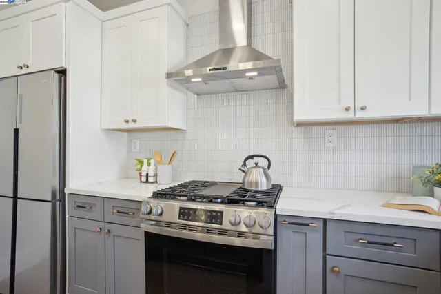 a kitchen with stainless steel appliances granite countertop a stove a refrigerator and a white cabinets