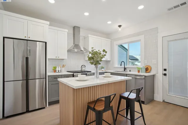 a kitchen with a sink a refrigerator a stove and white cabinets with wooden floor