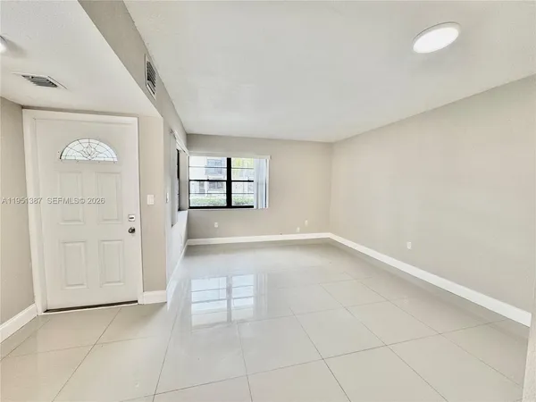 a view of a refrigerator in kitchen and an empty room