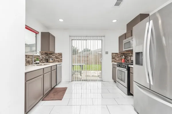 a kitchen with stainless steel appliances granite countertop a refrigerator oven a sink dishwasher and white cabinets with wooden floor