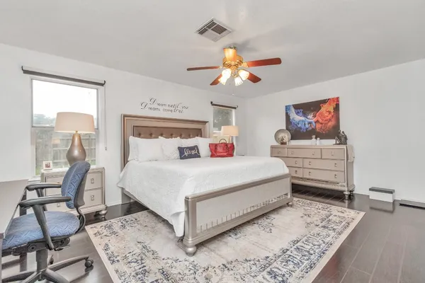 a bedroom with a bed a chair and potted plant on the table