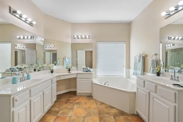 a large white bathroom with a large tub sink vanity granite and a large mirror