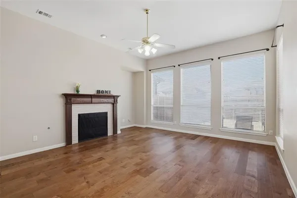 a view of an empty room with wooden floor fireplace and a window