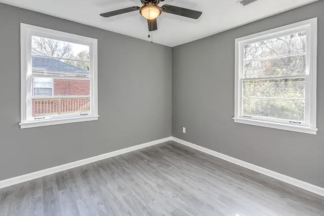 a view of an empty room with wooden floor and a window