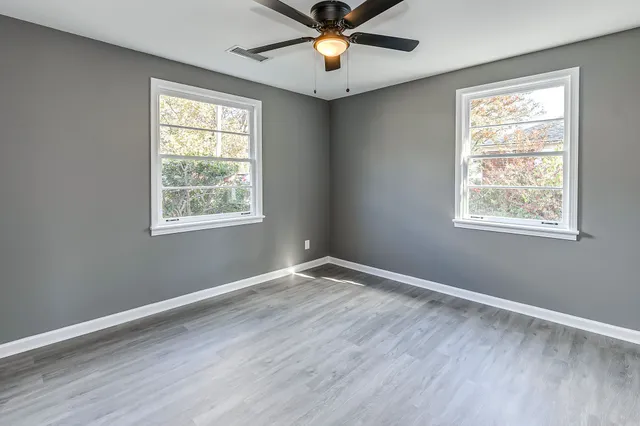 a view of an empty room with window and wooden floor