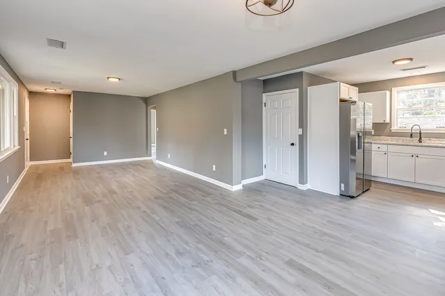 a view of an empty room with window wooden floor and cabinet