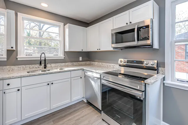 a kitchen with granite countertop a stove a sink and a microwave