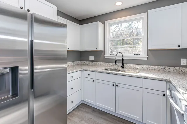 a kitchen with granite countertop white cabinets and a sink