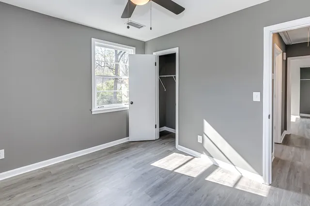 a view of empty room with wooden floor and fan