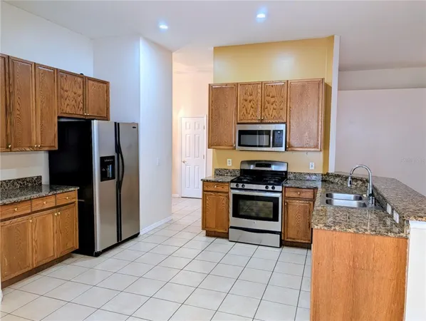 a kitchen with granite countertop a refrigerator and a stove top oven
