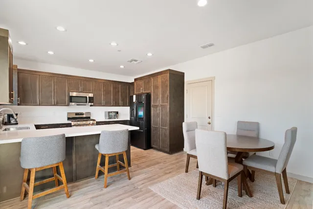 a kitchen with a dining table chairs and refrigerator