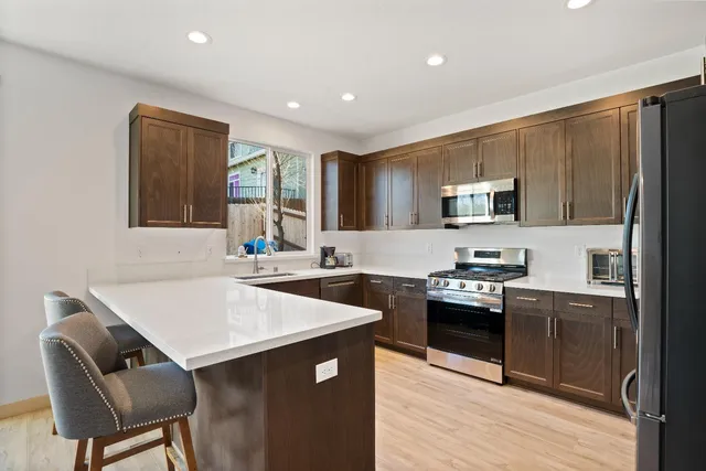 a kitchen with stainless steel appliances granite countertop a sink a stove a refrigerator cabinets and a dining table