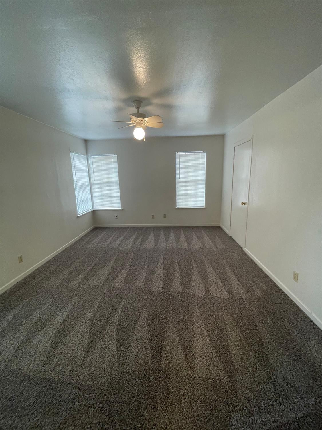 2121 33rd Street, Unit A Lubbock, TX 79411 - Photo 4 of 6 an empty room with windows and fan