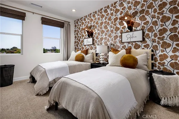 a bedroom with two beds and a lamp next to a window