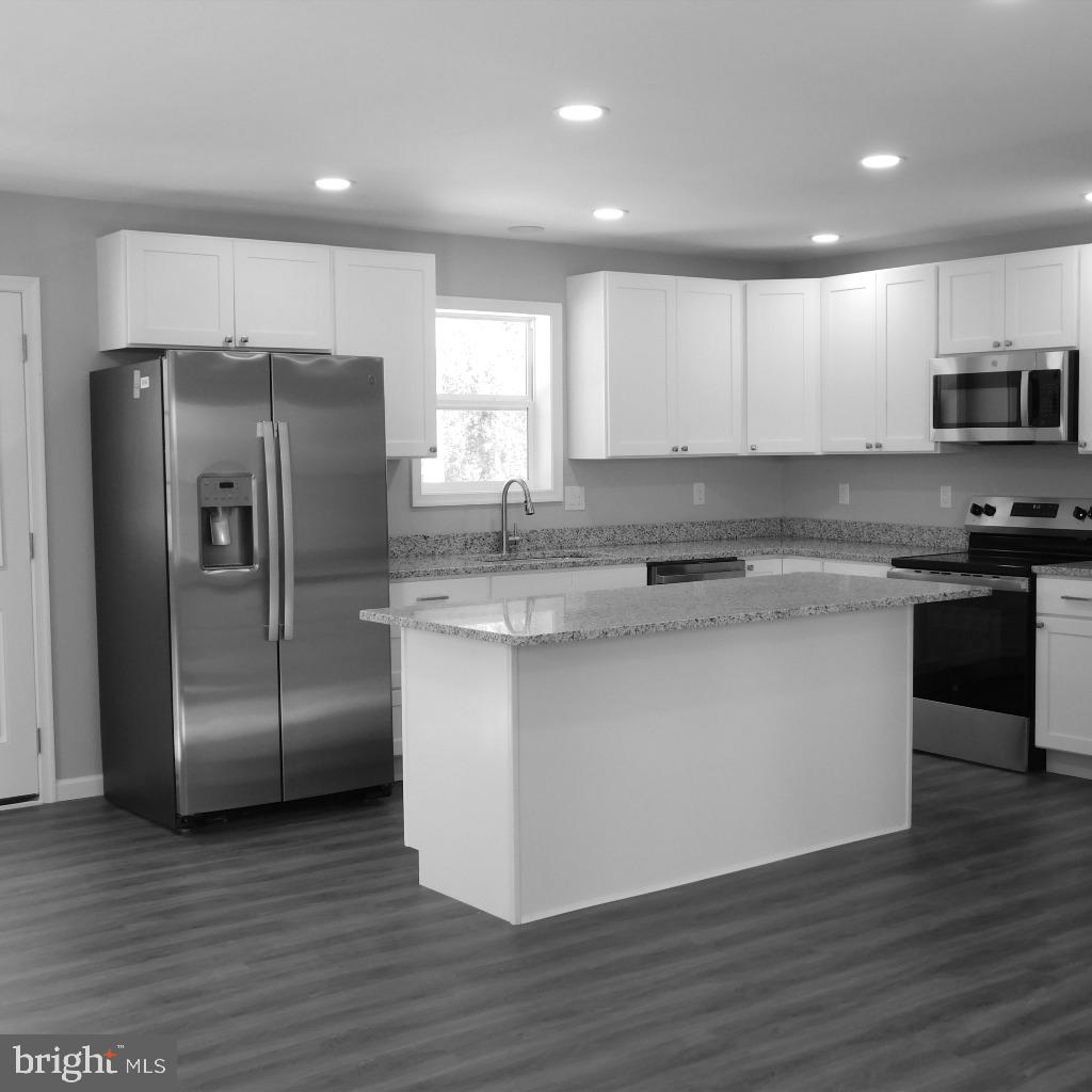 9458 Benson Road Lincoln, DE 19960 - Photo 4 of 38 a kitchen with stainless steel appliances granite countertop a refrigerator a sink a stove a microwave and white cabinets with wooden floor