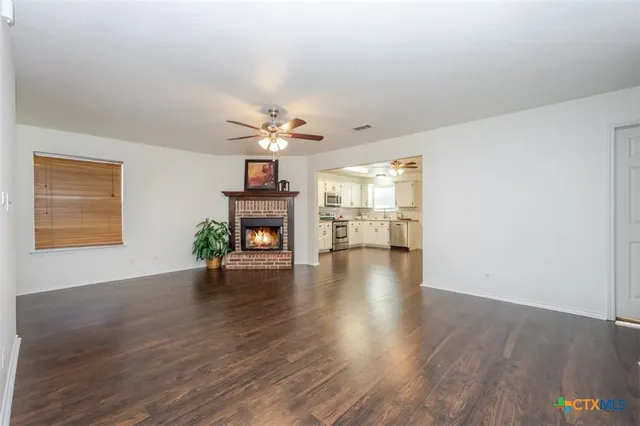 a view of a livingroom with wooden floor a fireplace and window