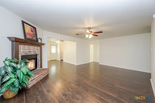 a view of an empty room with wooden floor and a fireplace