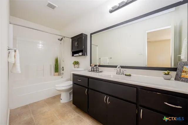 a bathroom with a double vanity sink and mirror with toilet