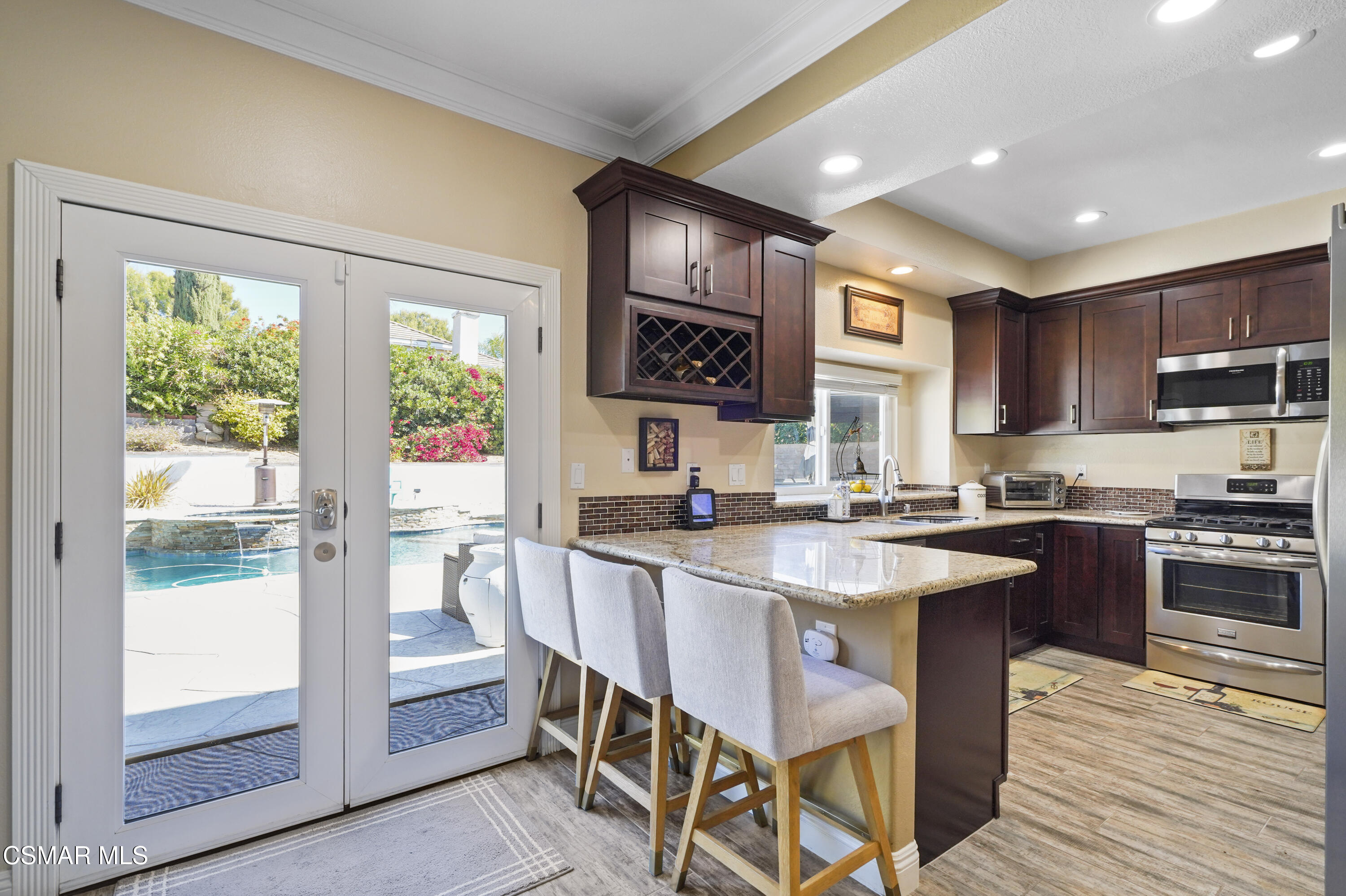 14291 Clemson Street Moorpark, CA 93021 - Photo 7 of 23 a kitchen with stainless steel appliances granite countertop a stove top oven a sink dishwasher a dining table and chairs with wooden floor