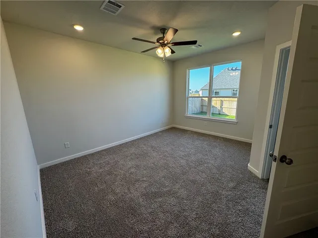 an empty room with a ceiling fan and window