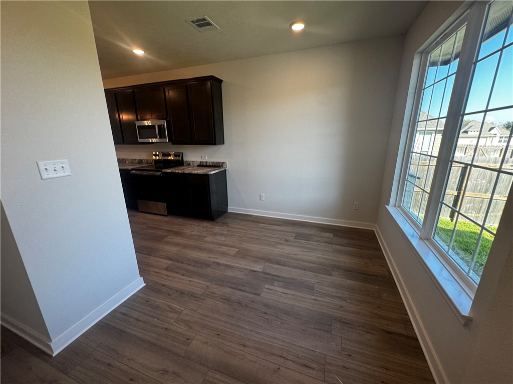 4795 Holm Oak Road Bryan, TX 77845 - Photo 4 of 17 Kitchen featuring stainless steel appliances, dark brown cabinetry, dark wood-style floors, recessed lighting, and light stone counters