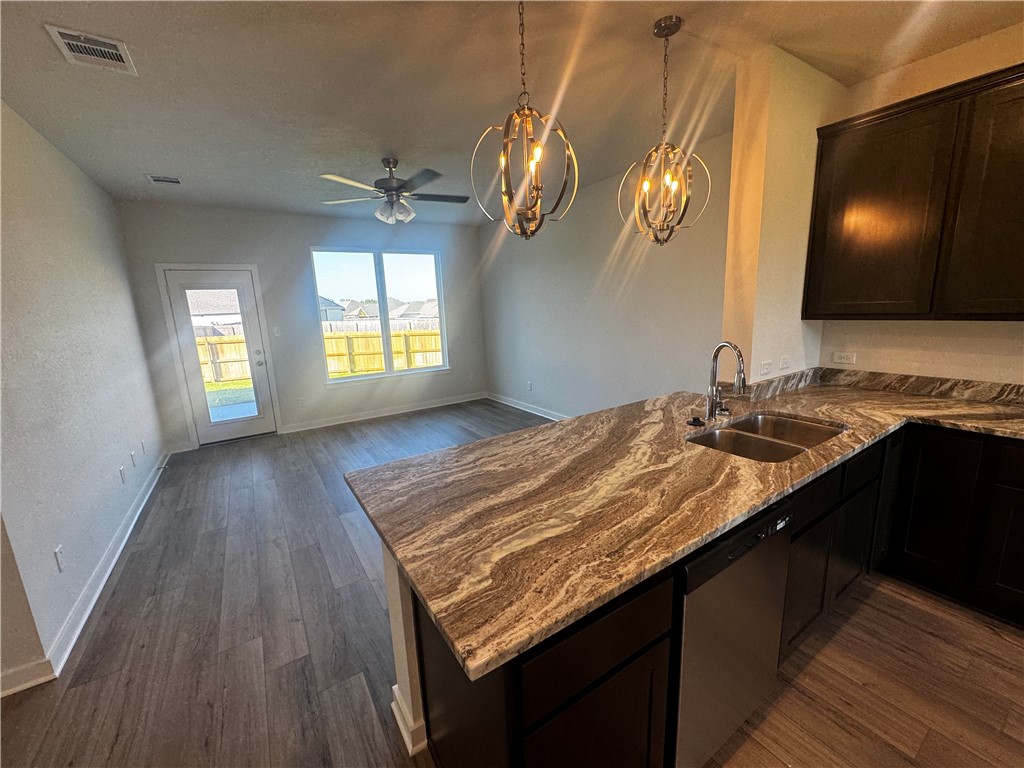 4795 Holm Oak Road Bryan, TX 77845 - Photo 6 of 17 Kitchen with dark stone countertops, a peninsula, dark wood-type flooring, stainless steel dishwasher, and a chandelier
