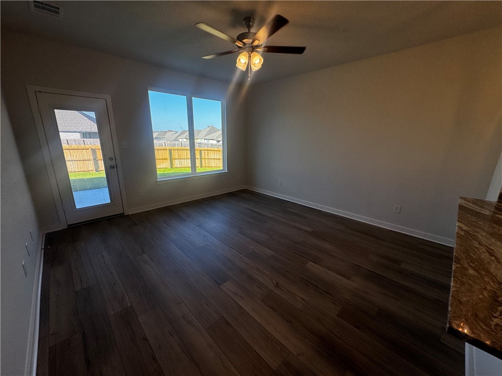 4795 Holm Oak Road Bryan, TX 77845 - Photo 7 of 17 Unfurnished room featuring dark wood-style floors, plenty of natural light, and a ceiling fan