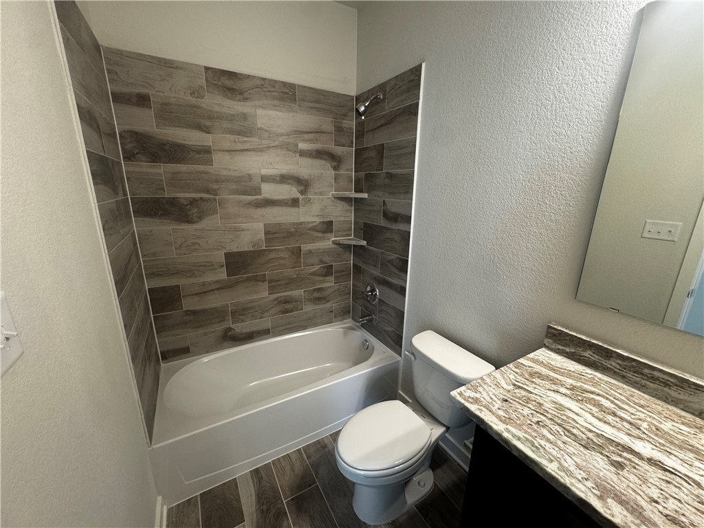4795 Holm Oak Road Bryan, TX 77845 - Photo 9 of 17 Full bathroom with a textured wall, vanity, wood finish floors, and shower combination