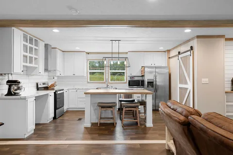 a kitchen with stainless steel appliances a table chairs refrigerator and cabinets