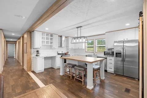 a kitchen with a refrigerator a sink dishwasher a stove and white cabinets with wooden floor