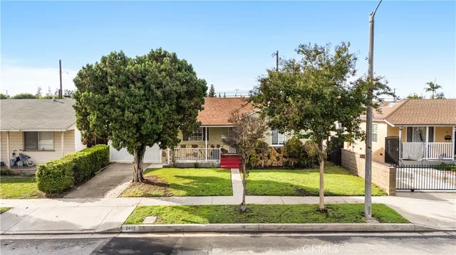 a view of a house with palm trees and a small yard