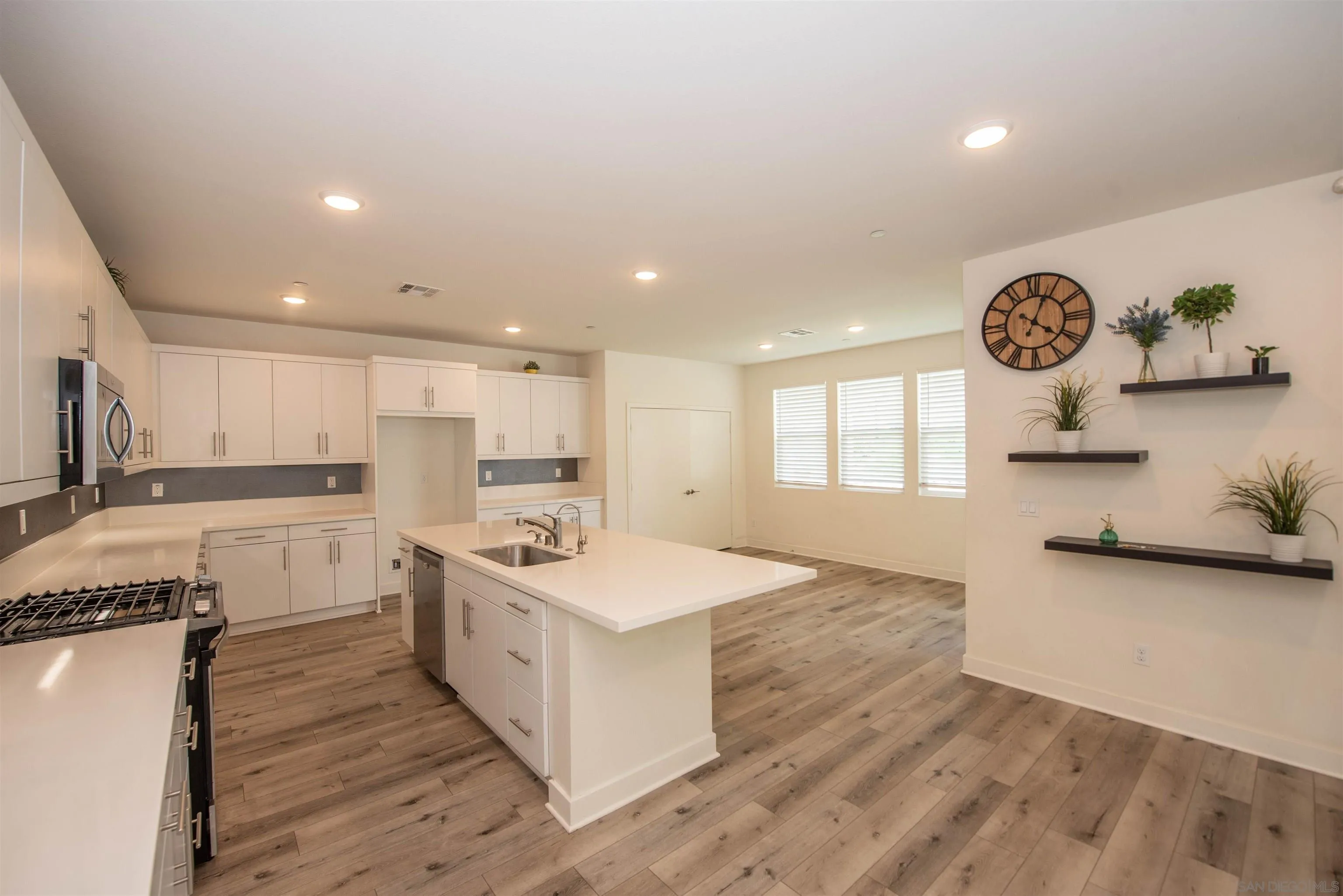 a large kitchen with stainless steel appliances a large counter top a stove and a sink