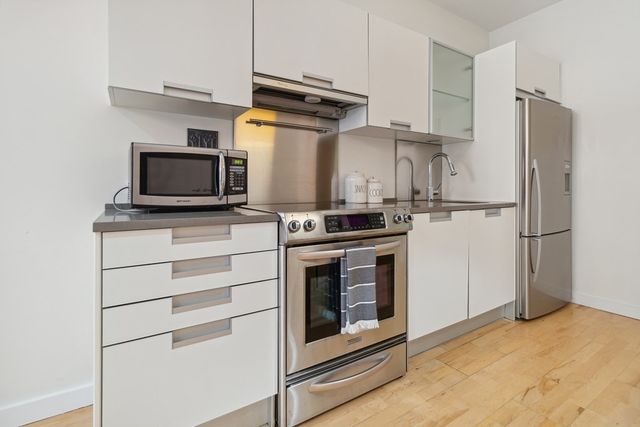 a kitchen with cabinets stainless steel appliances and wooden floor