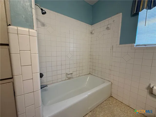 a white bath tub sitting next to a white sink and vanity